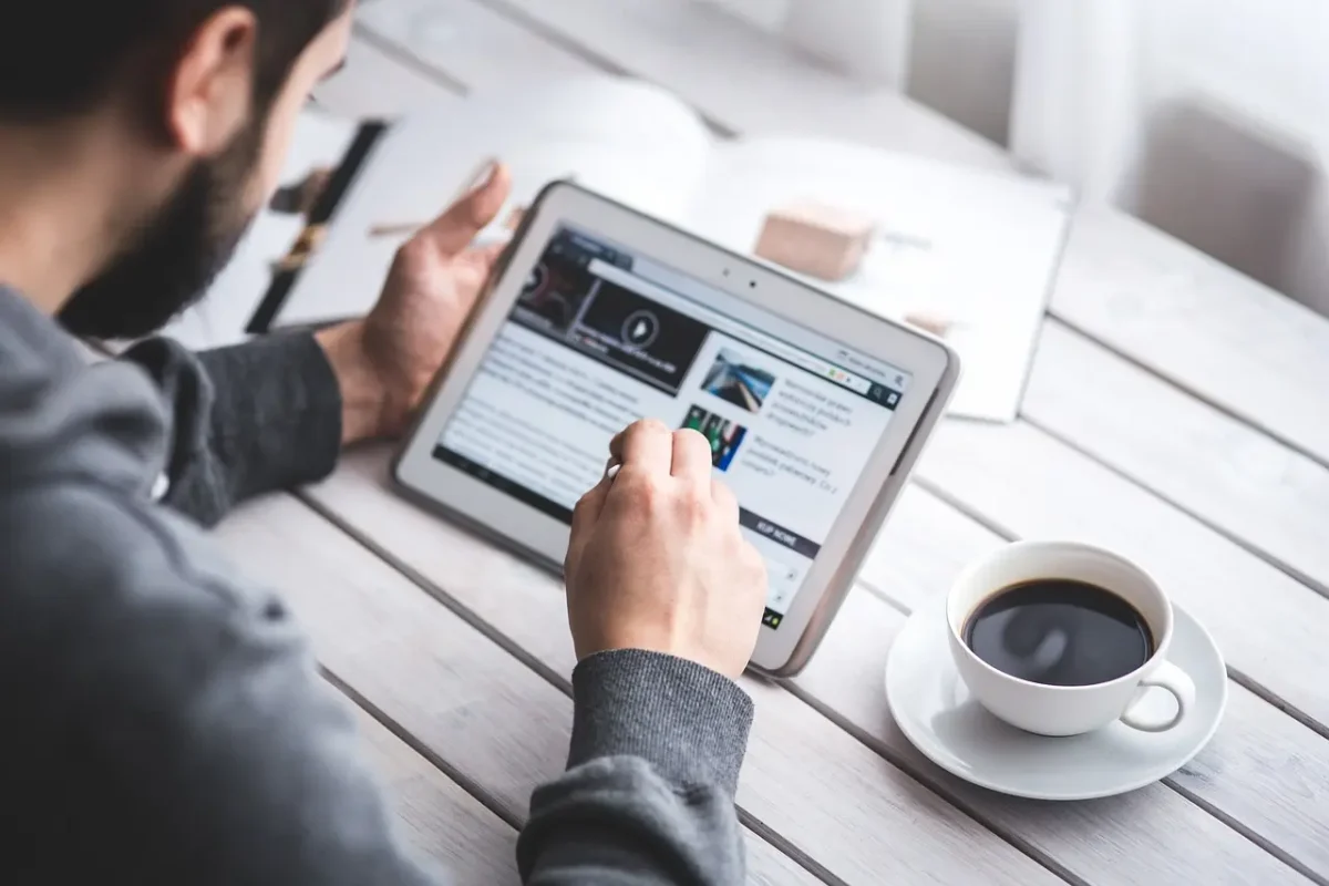 Person browsing a modern website on a tablet with coffee on a desk – LaunchPad Web Designs blog banner image