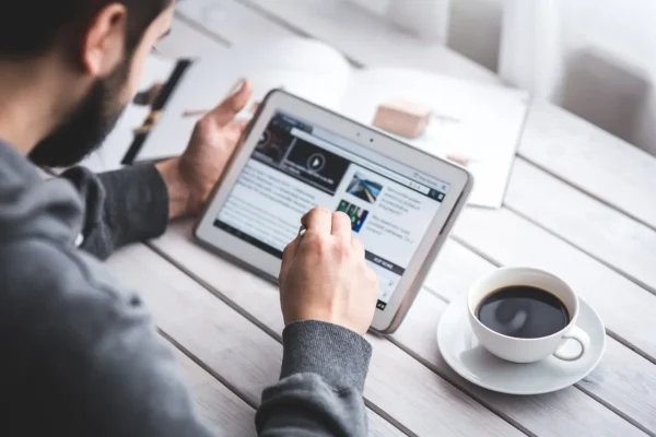 Person browsing a modern website on a tablet with coffee on a desk – LaunchPad Web Designs blog banner image