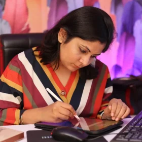 A female freelancer works at a desk, using a stylus to draw on a digital tablet while a keyboard sits next to it. This image represents website design and development services tailored for beginner freelancers and creative professionals who need a professional online presence to launch their careers.